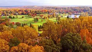 Aerial view of golf course in fall surrounded by autumn trees