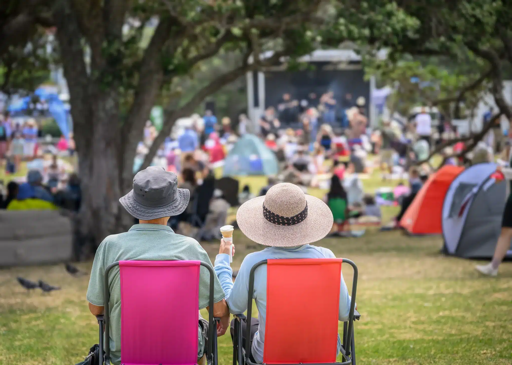 Two people in sun hats and lawn chairs enjoying outdoor music