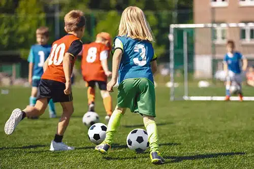 Group of children playing soccer on outdoor field